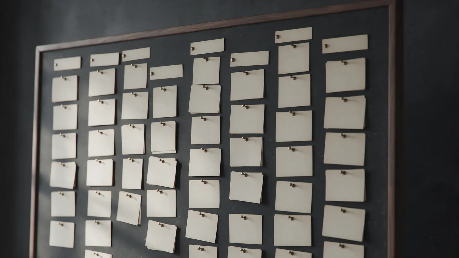 A dark wall board with rows of pinned paper cards